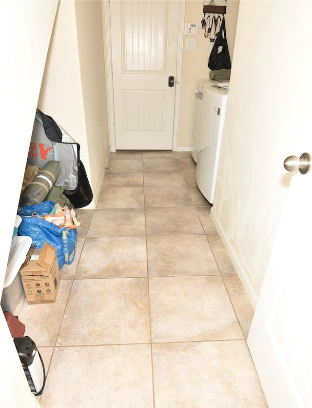 hall featuring light tile patterned floors, washer and clothes dryer, and baseboards