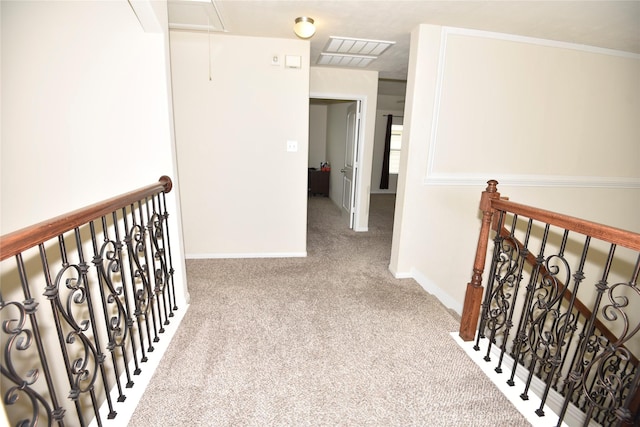 hallway featuring attic access, baseboards, carpet flooring, and an upstairs landing