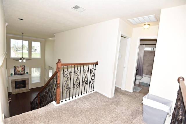 hallway with visible vents, carpet, an upstairs landing, and baseboards