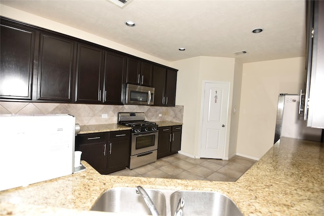 kitchen featuring light tile patterned floors, visible vents, decorative backsplash, stainless steel appliances, and a sink