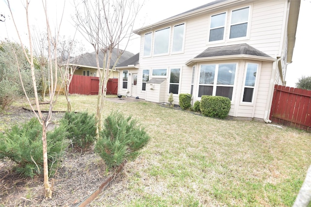 back of property with fence and a yard