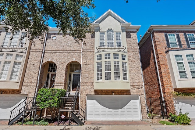 view of front facade with brick siding, stairway, decorative driveway, and a garage