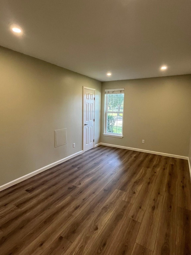 empty room with baseboards, dark wood finished floors, and recessed lighting