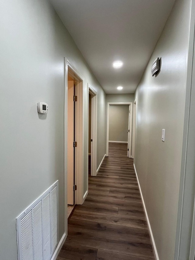 corridor featuring baseboards, visible vents, and dark wood finished floors