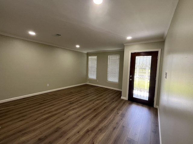 foyer entrance featuring dark wood-style floors, ornamental molding, visible vents, and baseboards