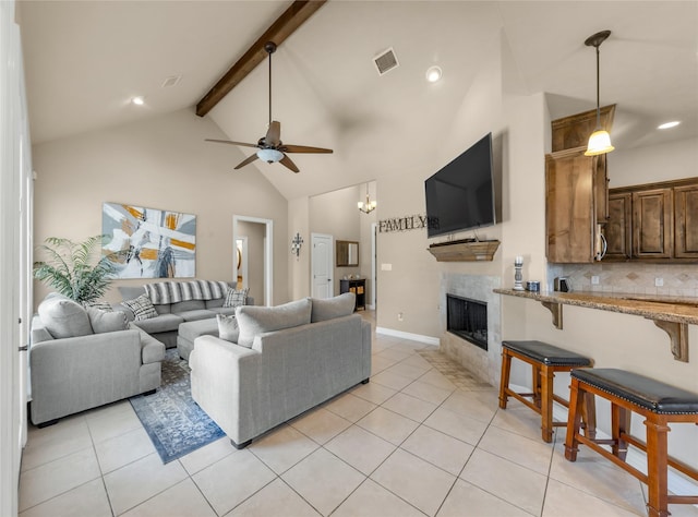 living room featuring visible vents, light tile patterned flooring, ceiling fan, a tile fireplace, and beamed ceiling