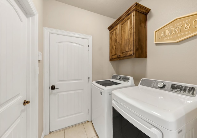 laundry area featuring light tile patterned floors, cabinet space, and washer and dryer