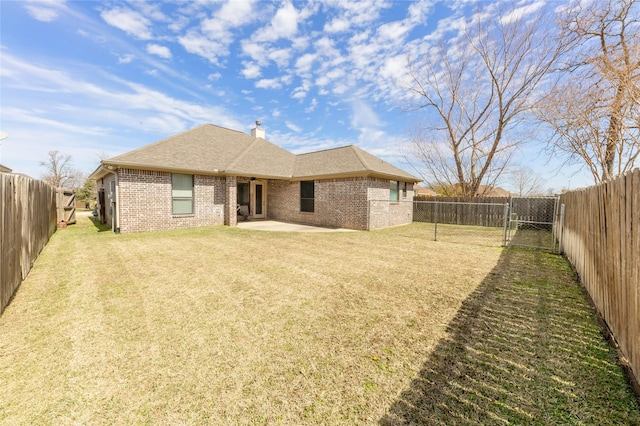 back of property with a patio area, brick siding, a lawn, and a fenced backyard