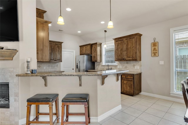 kitchen with a peninsula, plenty of natural light, a breakfast bar area, and stainless steel fridge with ice dispenser