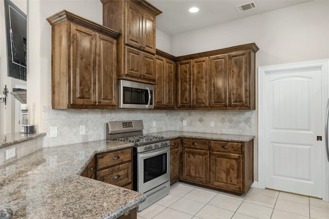 kitchen featuring visible vents, decorative backsplash, appliances with stainless steel finishes, light tile patterned flooring, and light stone countertops