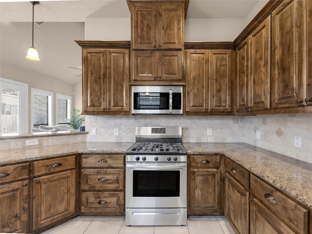 kitchen with appliances with stainless steel finishes, light tile patterned flooring, backsplash, and light stone counters