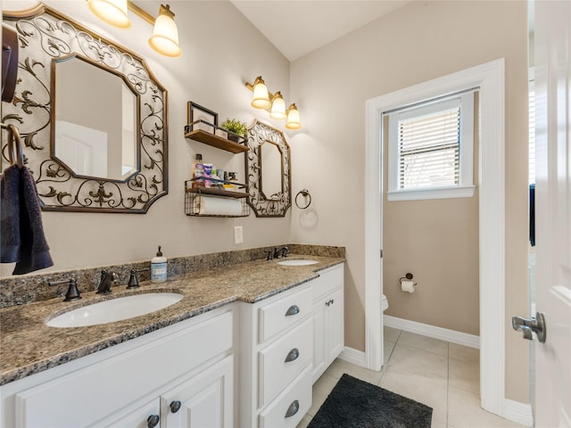 bathroom with double vanity, toilet, a sink, and tile patterned floors