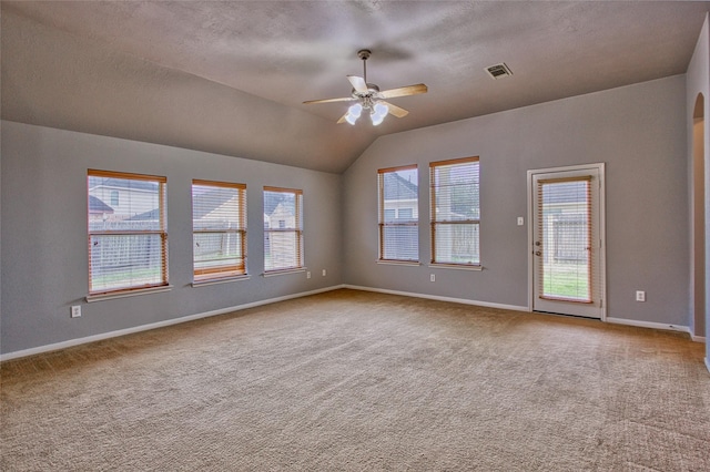 empty room with a ceiling fan, visible vents, vaulted ceiling, baseboards, and carpet