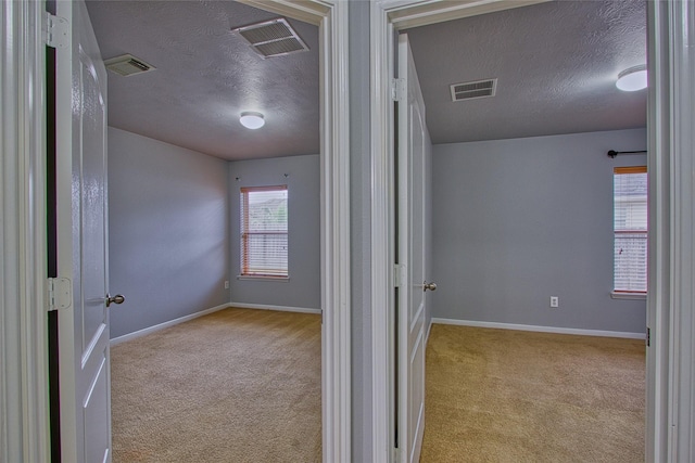 hall with baseboards, visible vents, and carpet flooring