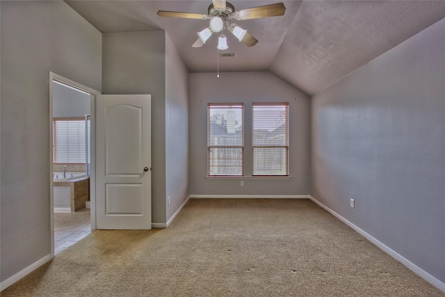 additional living space featuring lofted ceiling, light colored carpet, visible vents, a ceiling fan, and baseboards