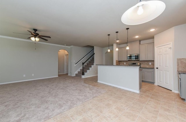 kitchen featuring arched walkways, decorative light fixtures, tasteful backsplash, gray cabinets, and stainless steel microwave