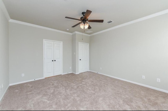 unfurnished bedroom featuring crown molding, a closet, visible vents, carpet flooring, and baseboards