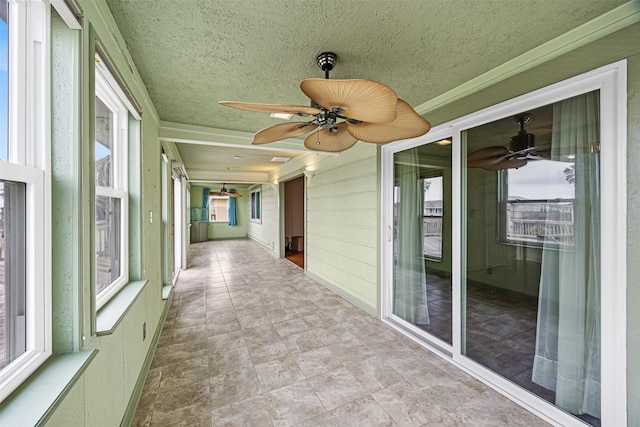 unfurnished sunroom featuring a ceiling fan