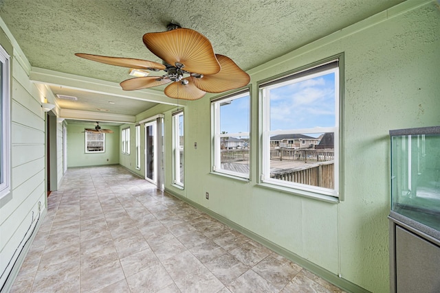 unfurnished sunroom featuring a ceiling fan