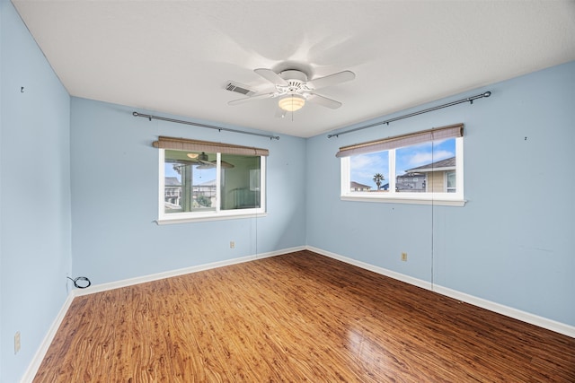 unfurnished room featuring a ceiling fan, wood finished floors, visible vents, and baseboards