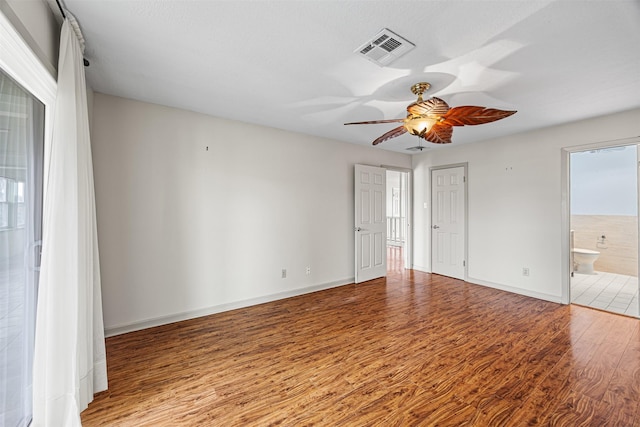 spare room featuring visible vents, a ceiling fan, baseboards, and wood finished floors