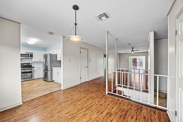 kitchen with visible vents, stainless steel appliances, light countertops, light wood-style floors, and white cabinetry