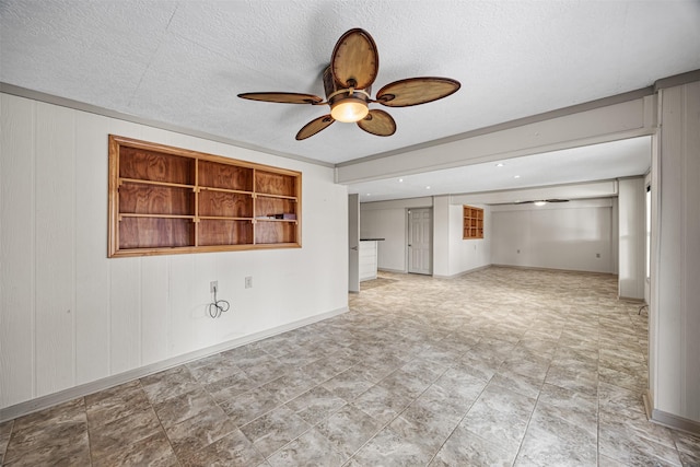 unfurnished living room featuring a ceiling fan, baseboards, and a textured ceiling