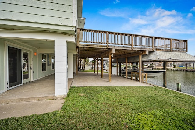 dock area with a patio area, boat lift, a yard, and a water view