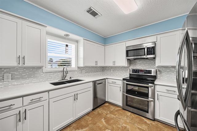 kitchen featuring visible vents, decorative backsplash, appliances with stainless steel finishes, white cabinetry, and a sink