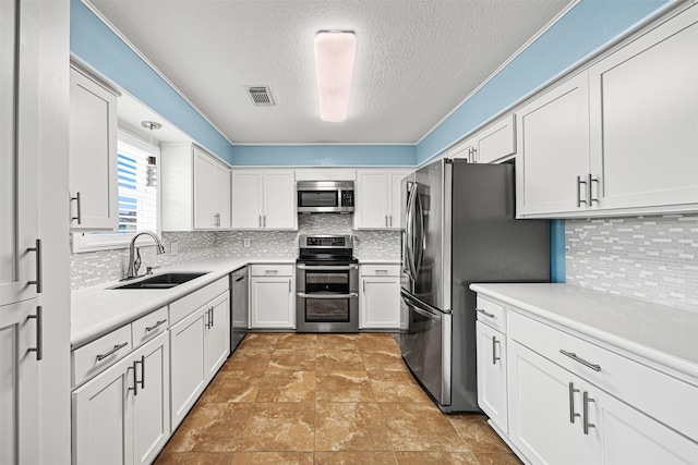 kitchen with visible vents, a sink, backsplash, appliances with stainless steel finishes, and white cabinets