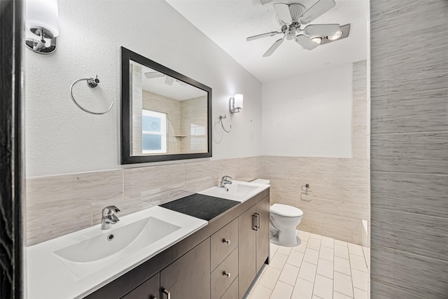 full bath featuring tile walls, toilet, double vanity, and a sink