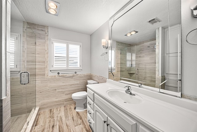 full bathroom featuring visible vents, a textured ceiling, tile walls, and a stall shower