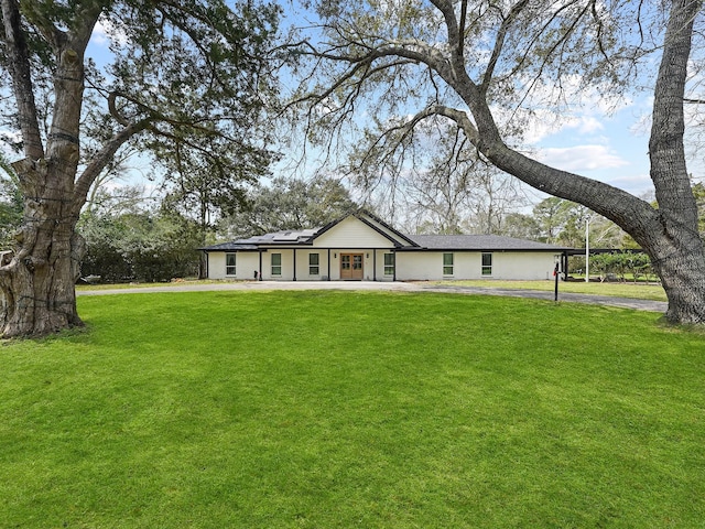 single story home featuring driveway, solar panels, and a front lawn