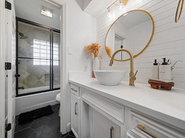 bathroom featuring tile patterned floors, toilet, vanity, and shower / bath combination with glass door