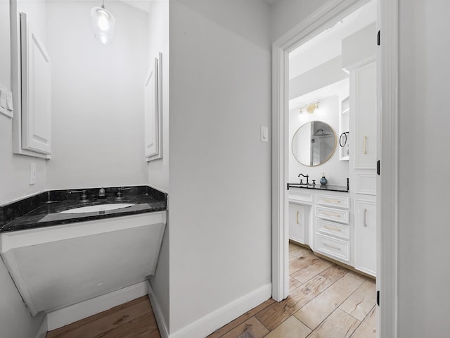 bathroom featuring vanity, wood finished floors, and baseboards