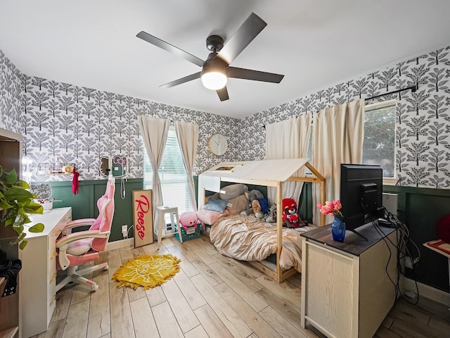 bedroom with baseboards, wallpapered walls, a ceiling fan, and wood finished floors