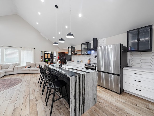 kitchen featuring wall chimney exhaust hood, light wood-type flooring, appliances with stainless steel finishes, and a sink