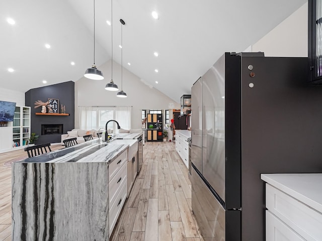 kitchen featuring a large island with sink, white cabinetry, light wood-type flooring, and freestanding refrigerator