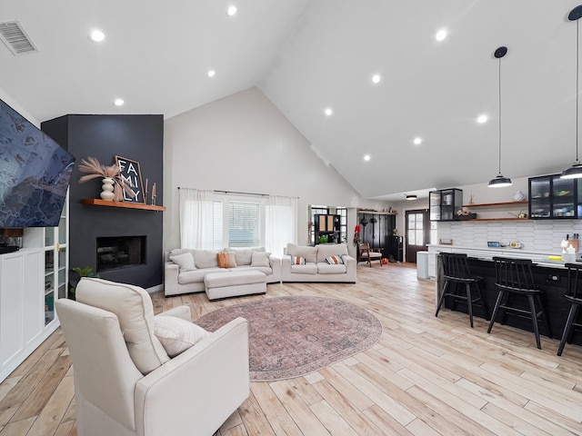 living room featuring light wood-type flooring, visible vents, plenty of natural light, and a fireplace