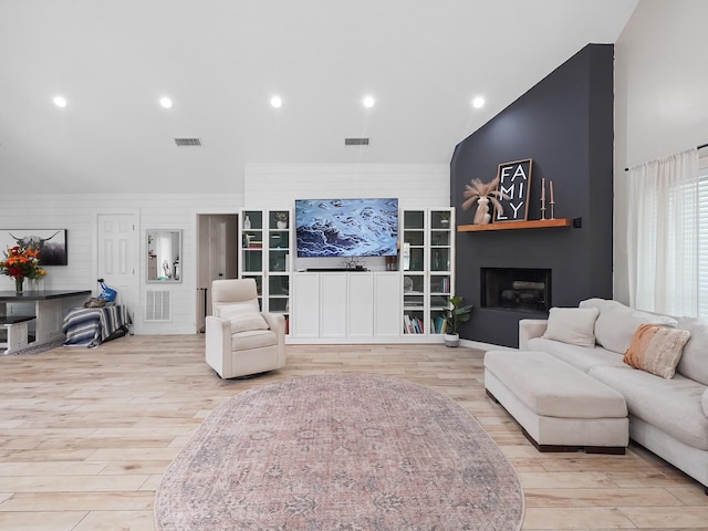 living area featuring visible vents, a fireplace, and wood finished floors