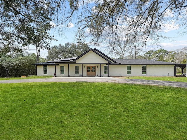 view of front facade with roof mounted solar panels, a front lawn, and driveway