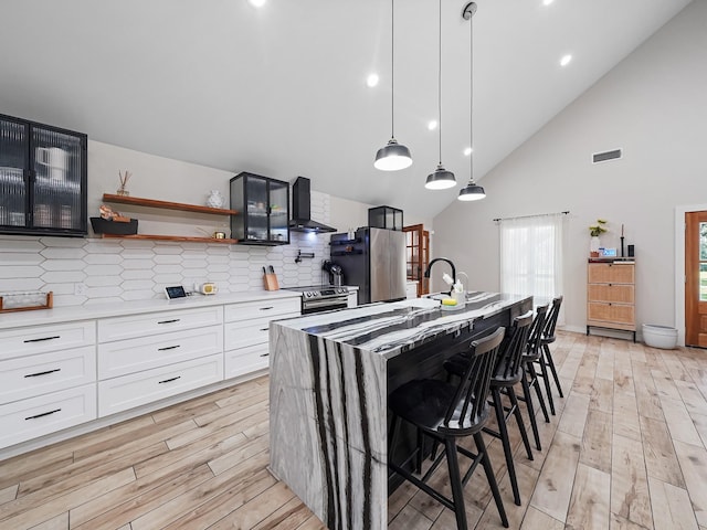 kitchen with stainless steel appliances, visible vents, wall chimney exhaust hood, and light countertops