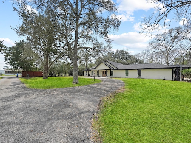 view of front of property featuring stucco siding, driveway, and a front lawn