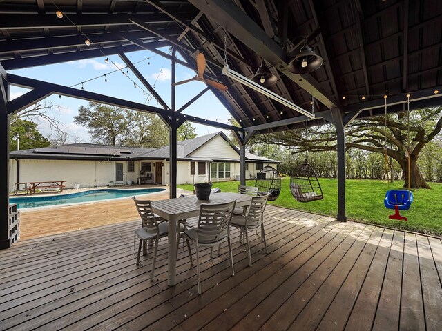 deck featuring an outdoor pool, a yard, and outdoor dining space