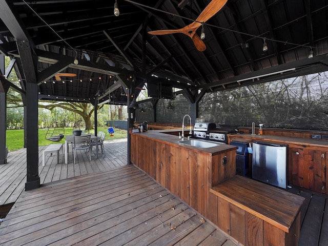 wooden deck featuring a lawn, a gazebo, grilling area, exterior kitchen, and outdoor dining area