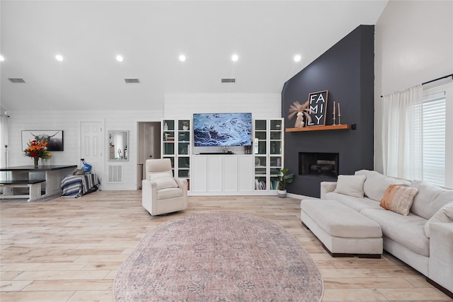 living area with visible vents, a fireplace, and light wood-type flooring