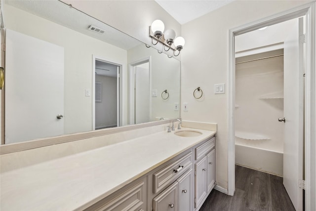 full bath with vanity, shower / tub combination, wood finished floors, and visible vents