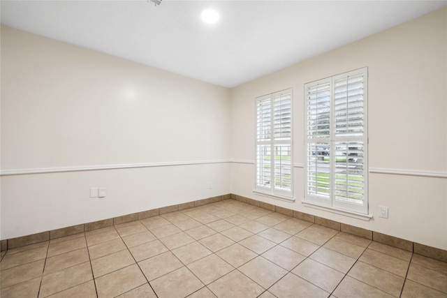 spare room with light tile patterned floors and baseboards