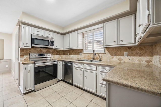 kitchen with a sink, stainless steel appliances, backsplash, and light tile patterned floors