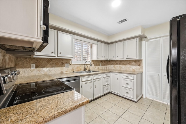 kitchen featuring light tile patterned floors, decorative backsplash, freestanding refrigerator, electric stove, and a sink